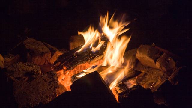 Nahaufnahme eines Lagerfeuers mit lodernden Flammen und glühenden Holzscheiten